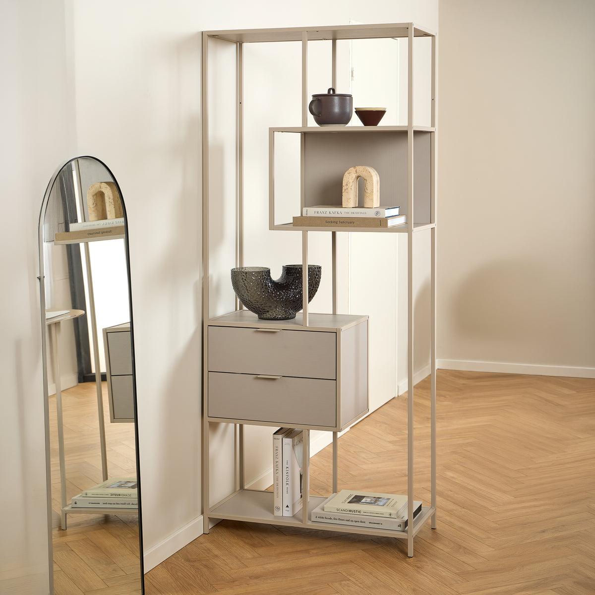 Skeleto bookcase, 77x185, grey melamine, in a bright room next to a mirror, with ceramics and books