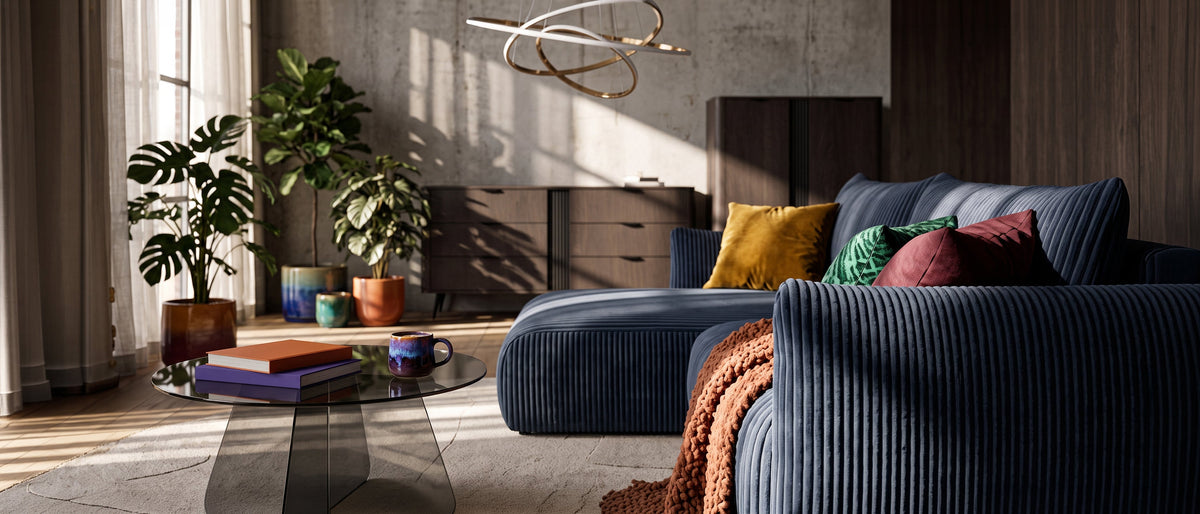 Modern living room with a navy Alloro corner sofa, an Aria Glass coffee table, dark Velia sideboards and a decorative Movimento pendant lamp