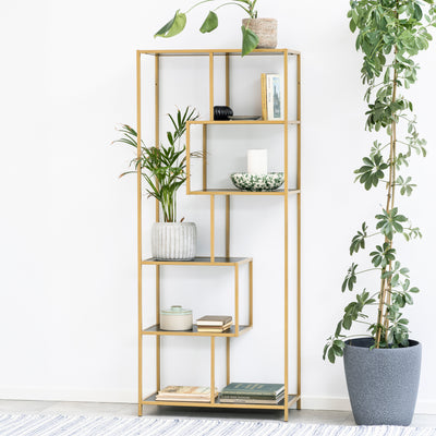 Skeleto bookcase, 77x185, black melamine (gold frame), against a white wall amongst potted plants – a glamorous bookcase