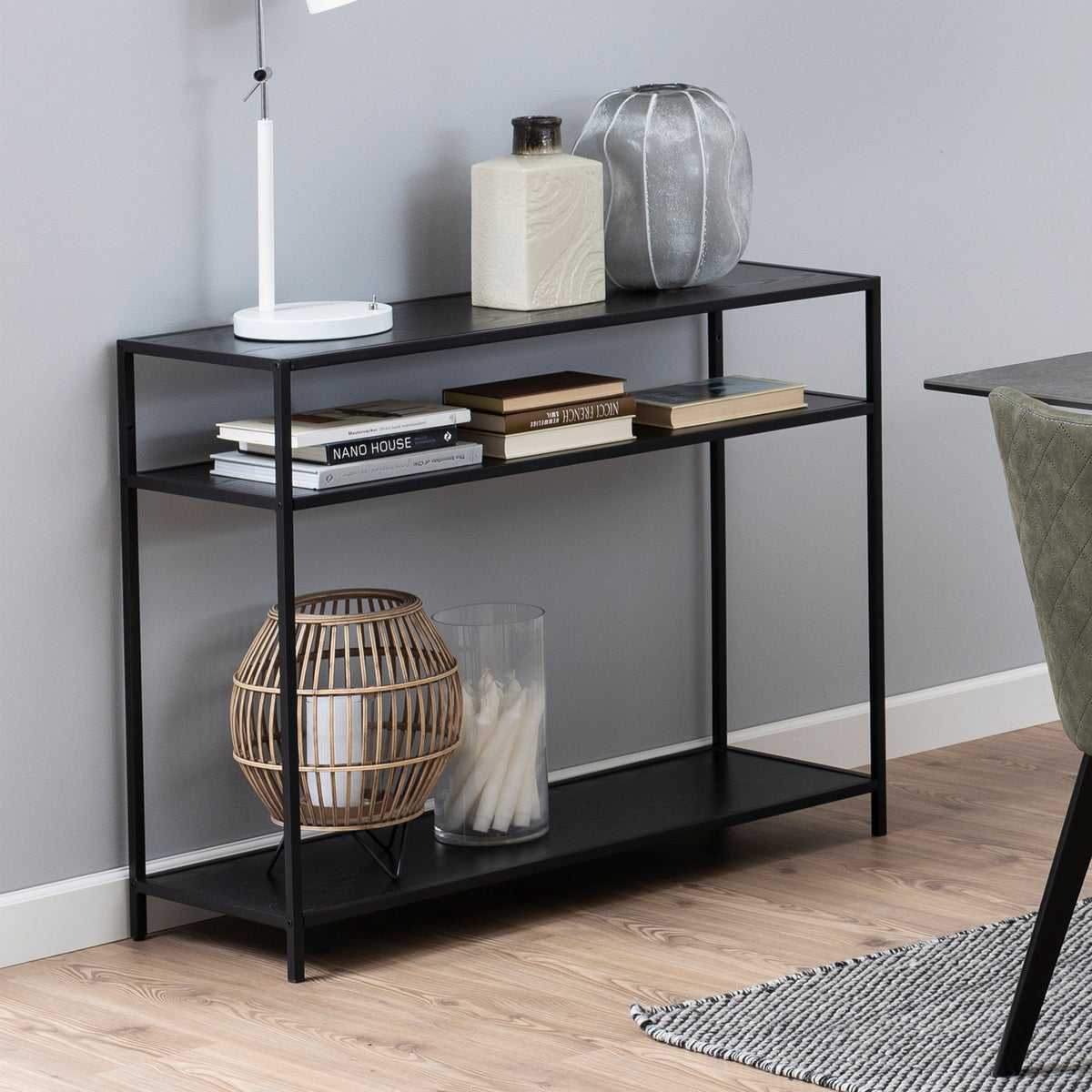 Skeleto 100x79 console table in black melamine, with books, a lamp and a lantern on the shelves, next to a chair by the table