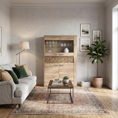 Korin display cabinet 102x160 in a living room with a grey sofa and a Persian-style rug – display cabinet for glasses